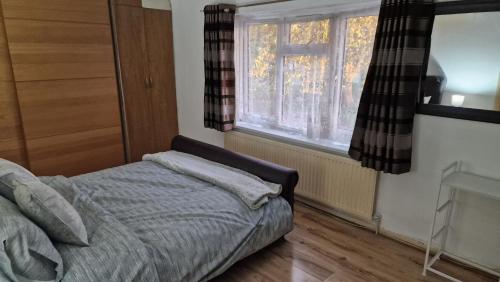 1 dormitorio con cama y ventana en Comfortable 2 bedroom house with free parking and great transport links en Dagenham