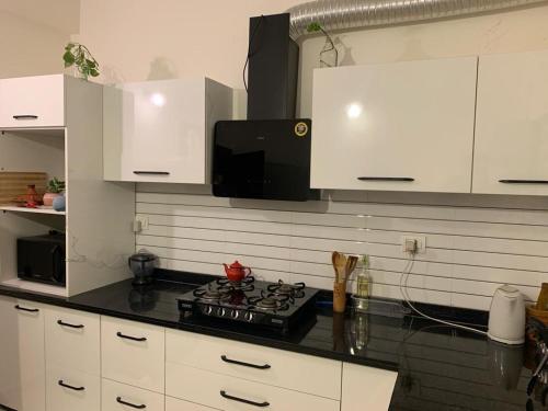 a kitchen with white cabinets and a stove top oven at Away From Home, Furnished Apartment in Bhopal