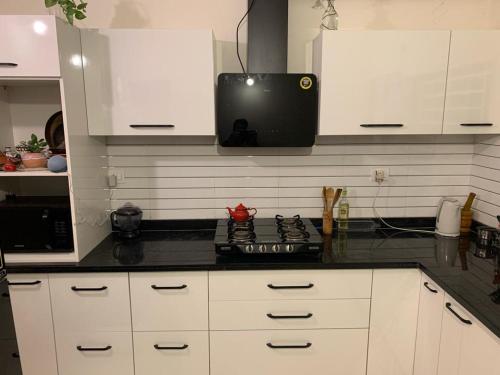 a kitchen with white cabinets and a black counter top at Away From Home, Furnished Apartment in Bhopal