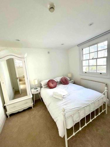 1 dormitorio con cama blanca y espejo grande en Fab split level Kensington Apartment en Londres