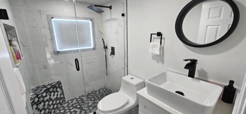 a bathroom with a toilet and a sink and a mirror at Private Cozy & Spacious Room at a house with pool in Tamarac