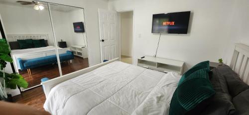 1 dormitorio con 1 cama y TV en la pared en Private Cozy & Spacious Room at a house with pool en Tamarac