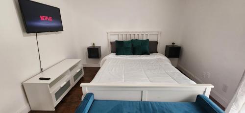 1 dormitorio con 1 cama blanca y TV en la pared en Private Cozy & Spacious Room at a house with pool en Tamarac