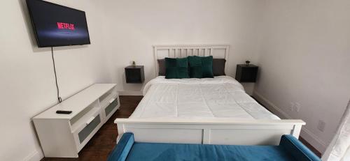 a bedroom with a white bed with a tv on the wall at Bright & Comfortable Private Room in a Family Home, Shared nice Bath in Tamarac