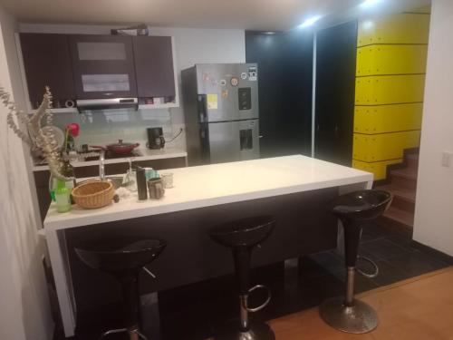 une cuisine avec un comptoir et deux tabourets de bar dans l'établissement Habitaciones Centro Histórico, ed, continental, à Bogotá