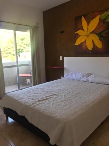Un dormitorio con una gran cama blanca y una ventana en Cabaña Privada en Comuna San Roque en Bialet Massé