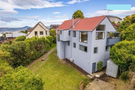 una casa blanca con techo rojo en un patio en Waverley Comfort en Dunedin