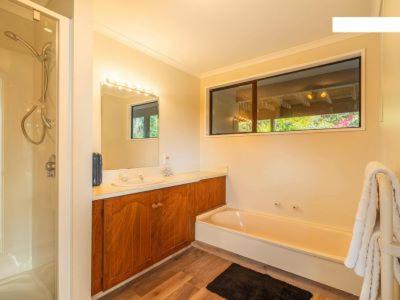 a bathroom with a tub and a sink and a mirror at Waverley Comfort in Dunedin