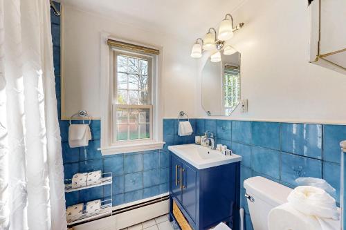 uma casa de banho em azulejos azuis com um lavatório e um espelho em Goldfinch Cottage em Newburyport