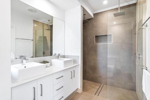 a white bathroom with two sinks and a shower at Flagship Villa in Trinity Beach