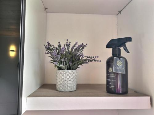 a bottle of soap and a vase of flowers on a shelf at Les gîtes de L'Isle Jourdain in Pujaudran