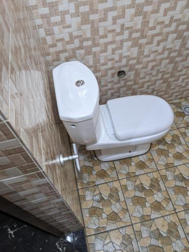 a bathroom with a toilet in a tiled wall at CHAMBRE ET SÉJOUR CLIMATISES WiFi Gratuit A 6 Nuitées de Réservation in Lomé