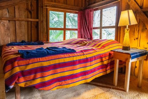 uma cama colorida num quarto de madeira com uma janela em La Iguana Perdida em Santa Cruz La Laguna