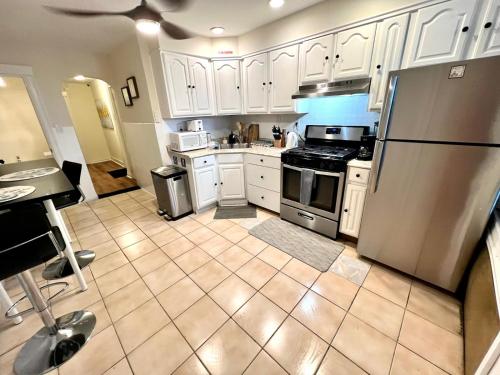 uma cozinha com armários brancos e um frigorífico de aço inoxidável em 8-A Diamond in Yonkers, NY em Yonkers