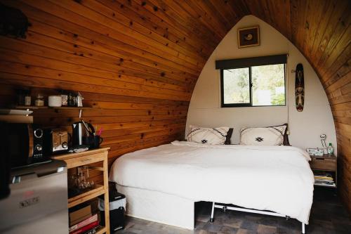 a bedroom with a bed in a room with wooden walls at The Dome Waikino in Waikino
