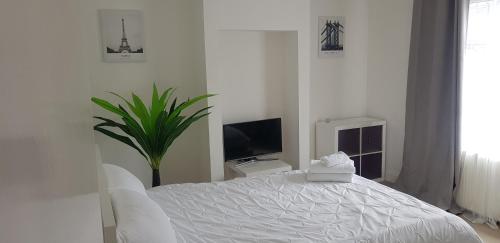 ein weißes Schlafzimmer mit einem weißen Bett und einem TV in der Unterkunft Mirandas Place in Gillingham