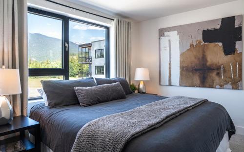 a bedroom with a bed and a large window at The Stoke Stopover - Revelstoke Condo with Hot Tub in Revelstoke