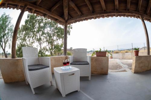 a patio with white chairs and a table with a glass of wine at Casa Giardinello in Ribera