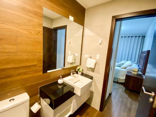 a bathroom with a sink and a mirror and a bed at Departamento Elegante y Relax by Torre Vento in Santa Cruz de la Sierra
