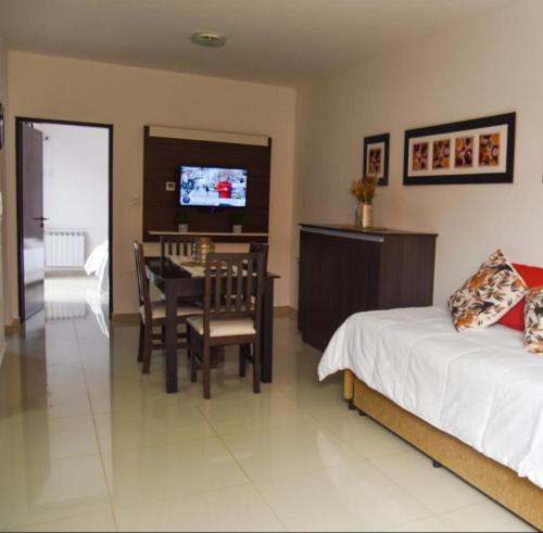 a bedroom with a bed and a table and a television at Mendoza Aparts - Con cochera incluida in Villa María