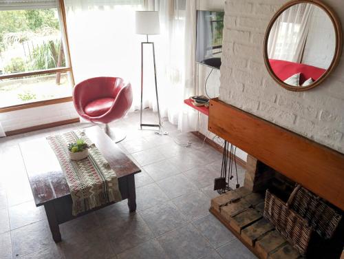 a living room with a fireplace and a red chair at El sabia in Piriápolis