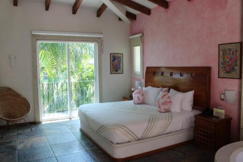 sypialnia z łóżkiem z różowymi ścianami i oknem w obiekcie Nequi Hotel Boutique w mieście Tepoztlán