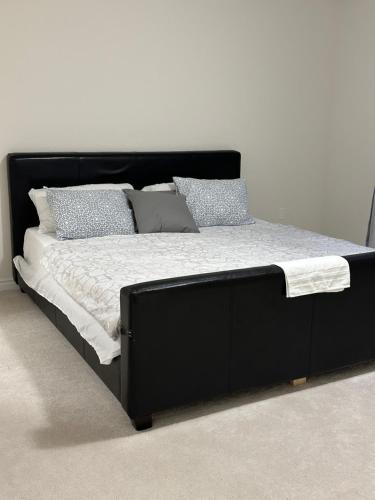uma cama com uma moldura preta e almofadas em 4 Bedrooms new house sleep 12 fury friends welcome em Cataratas do Niágara