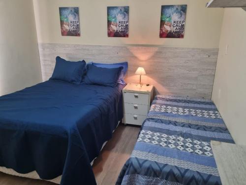 1 Schlafzimmer mit 2 Betten mit blauer Bettwäsche und einem Nachttisch in der Unterkunft Apartamento 50 metros do Mar da Brava Floripa in Florianópolis