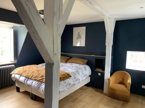 - une chambre avec des murs bleus, un lit et une chaise dans l'établissement Le Grand Monnet - Parc - 16 personnes - Rêve au Mans, à Coulaines