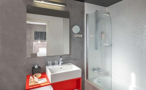 ein Badezimmer mit einem weißen Waschbecken und einer Dusche in der Unterkunft Hotel Litteraire Alexandre Vialatte, BW Signature Collection in Clermont-Ferrand