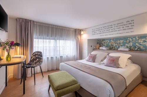 ein Hotelzimmer mit einem großen Bett und einem Schreibtisch in der Unterkunft Hotel Litteraire Alexandre Vialatte, BW Signature Collection in Clermont-Ferrand