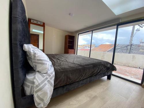 um quarto com uma cama e uma grande janela em Departamento Enorme Centro Histórico ecualodge9 em Cuenca