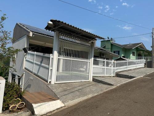 a white fence in front of a house at Casa Amor Perfeito com Jacuzzi- Próximo ao Parque Termal in Piratuba