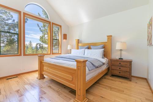 a bedroom with a wooden bed and two windows at Goldmine - Luxury Northstar 4BR- Shuttle to Slopes- Gym Access- Pet Friendly in Truckee