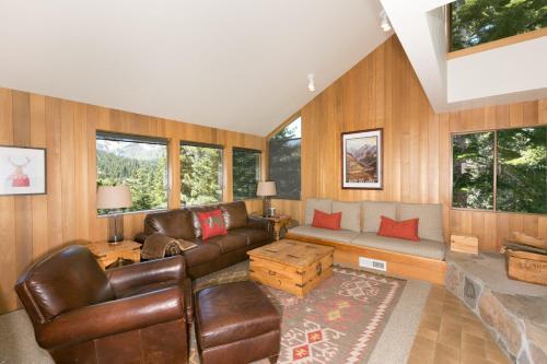 a living room with brown leather furniture and windows at Juniper at Alpine - Private Hot tub, Pet Friendly & Free Shuttle to Slopes in Olympic Valley
