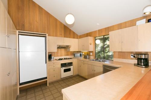 a kitchen with wooden cabinets and a white refrigerator at Juniper at Alpine - Private Hot tub, Pet Friendly & Free Shuttle to Slopes in Olympic Valley