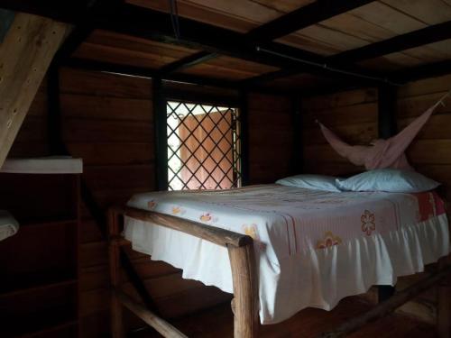 a bed in a log cabin with a window at Hostal Té de Menta in Muisne