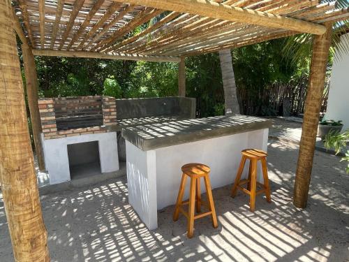 a outdoor bar with two stools under a wooden pergola at Casa Mandakarú in Icapuí