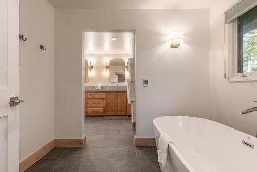 Baño blanco con bañera y lavamanos en Lupine Lodge at Tahoe Park on the West Shore - Hot Tub, Beach Access, Near Ski Resorts! en Tahoe City