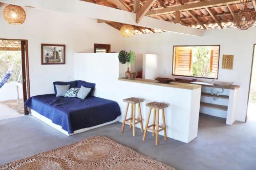 a bedroom with a bed and a counter and stools at Casa Mandakarú in Icapuí