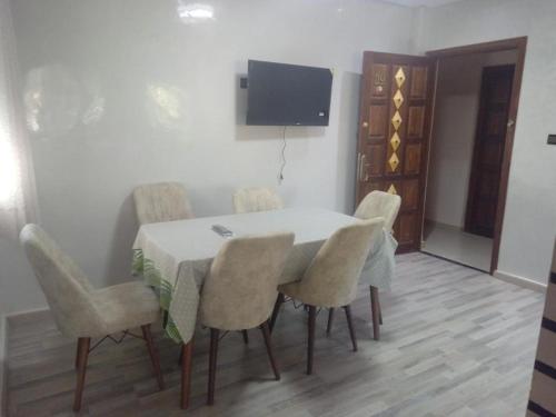 einen Esstisch mit Stühlen und einen TV an der Wand in der Unterkunft Imouzzer kandar in Imouzzer du Kandar