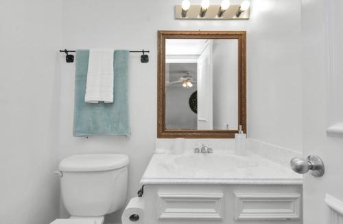 a white bathroom with a toilet and a mirror at Peaceful Queen Master Suite in Houston