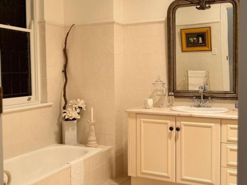 uma casa de banho com uma banheira, um lavatório e um espelho. em 23 on Windsor em Hahndorf