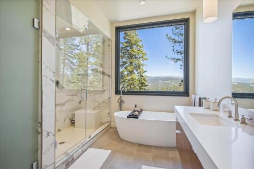 baño con bañera y ducha y ventana grande en Soaring Peak at Northstar- Endless Views at this Deluxe Ski-in Ski-out Northstar Residence en Truckee