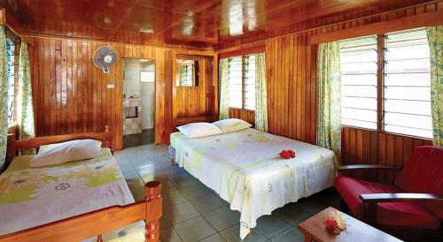 two beds in a room with wooden walls and windows at Korovou Eco Tour Resort in Naviti Island