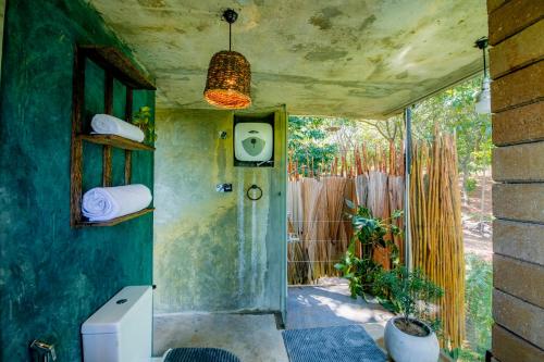 a bathroom with a toilet in a room with a fence at Heavens Acres Lodge in Matale