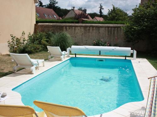- une piscine avec 2 chaises et un banc dans l'établissement Charmante maison avec piscine chauffée, cour fermée, proche Dreux et Chartres - FR-1-581-6, à Le Boullay-Thierry