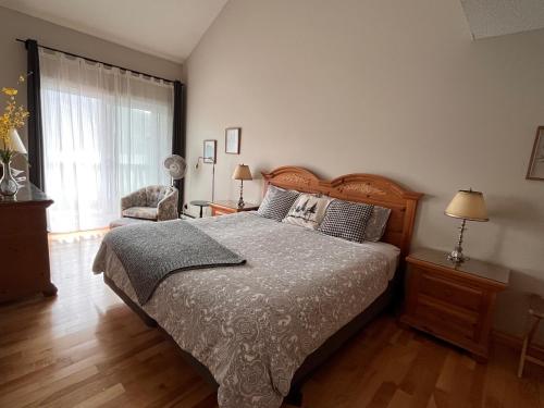 a bedroom with a bed and a chair and a window at Cozy 2 bedrooms condo with stunning Mont Tremblant mountain and lakeview in Mont-Tremblant