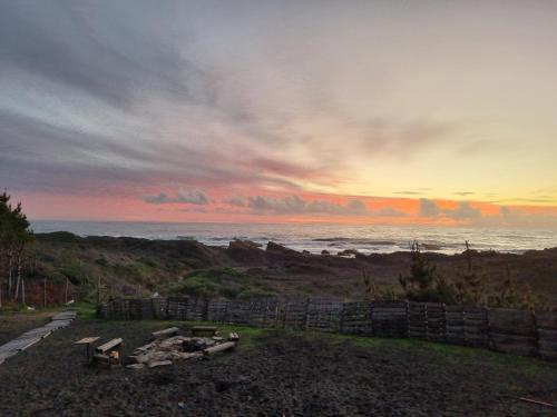 a sunset over the ocean with a fire pit at Casa Curanipe in Curanipe