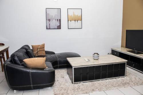 a living room with a black leather chair and a coffee table at Enka Flat Hotel in Abidjan